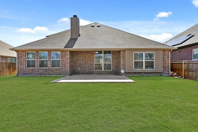 back of house with a patio, a fenced backyard, a yard, roof with shingles, and a chimney