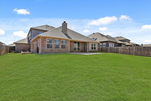 rear view of property with a fenced backyard, brick siding, a shingled roof, a yard, and a patio area