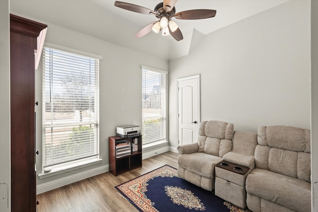 living area with lofted ceiling, light wood-style floors, baseboards, and a ceiling fan