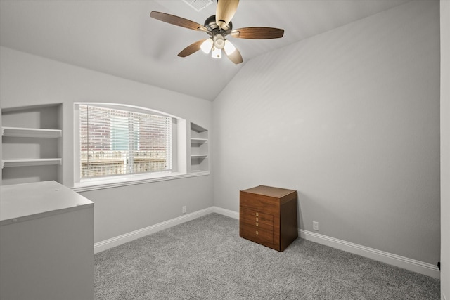 carpeted spare room featuring lofted ceiling, built in shelves, baseboards, and a ceiling fan