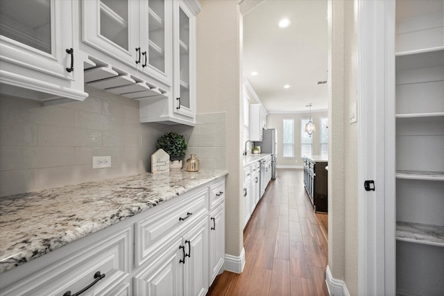 kitchen featuring decorative backsplash, light stone counters, white cabinets, glass insert cabinets, and dark wood-style flooring