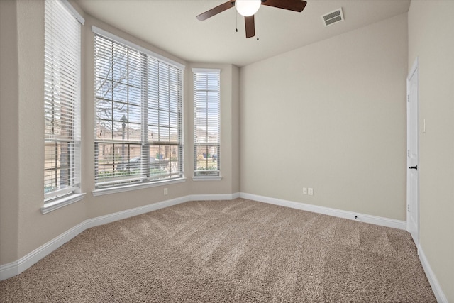 unfurnished room with visible vents, carpet floors, a healthy amount of sunlight, and ceiling fan