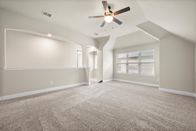 empty room featuring visible vents, lofted ceiling, baseboards, light colored carpet, and ceiling fan