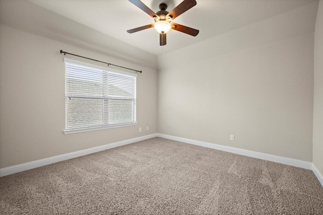 carpeted spare room with a ceiling fan and baseboards