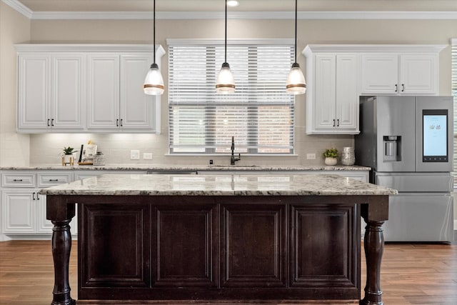 kitchen with crown molding, stainless steel fridge with ice dispenser, wood finished floors, white cabinetry, and a sink