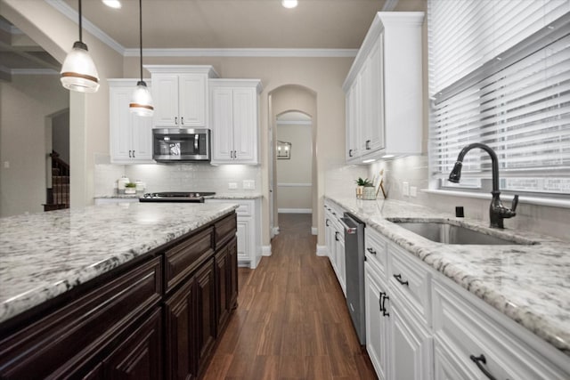 kitchen with arched walkways, ornamental molding, a sink, appliances with stainless steel finishes, and white cabinetry