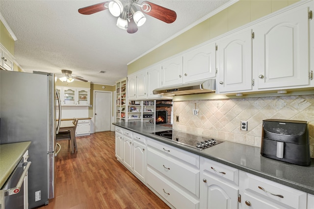 kitchen with freestanding refrigerator, dark countertops, under cabinet range hood, and black electric stovetop