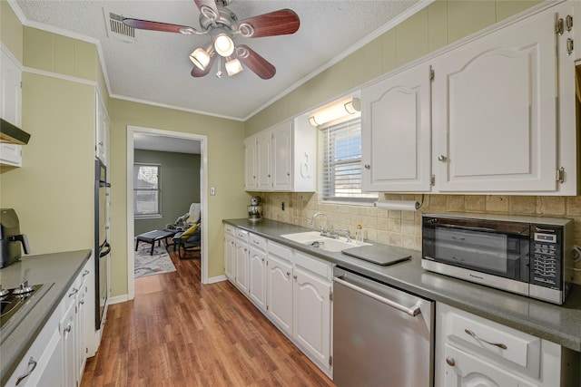 kitchen featuring a sink, white cabinetry, light wood-style floors, appliances with stainless steel finishes, and crown molding