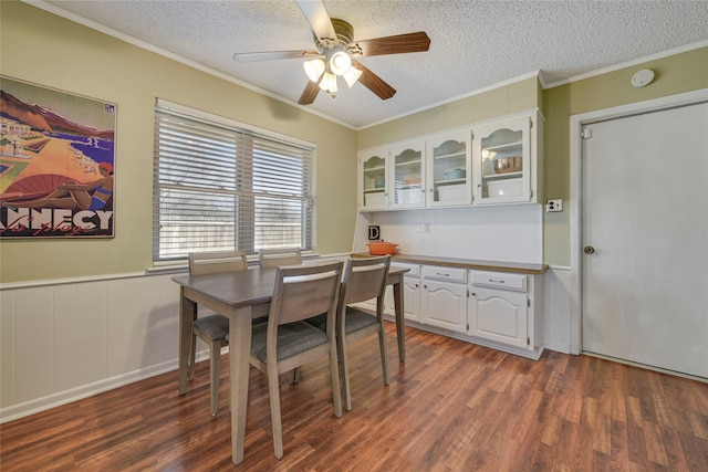 dining space with a textured ceiling, dark wood-type flooring, and ornamental molding