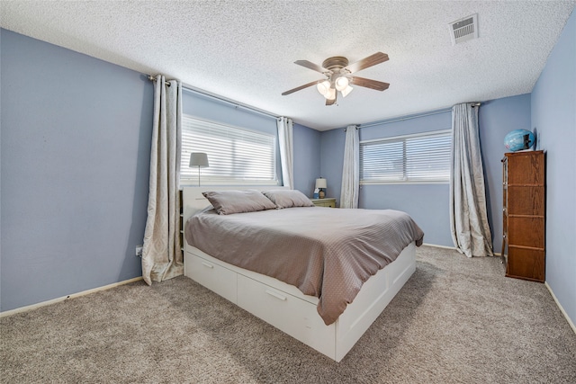 bedroom featuring carpet, a textured ceiling, visible vents, and a ceiling fan