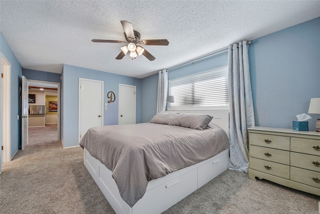 bedroom featuring a textured ceiling, light colored carpet, a ceiling fan, baseboards, and multiple closets