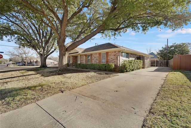 view of front of house with a gate, brick siding, fence, and concrete driveway