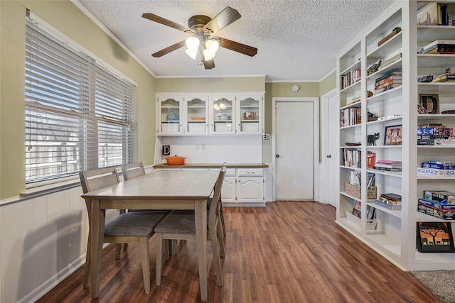 dining room with dark wood-style floors, ceiling fan, ornamental molding, and a textured ceiling