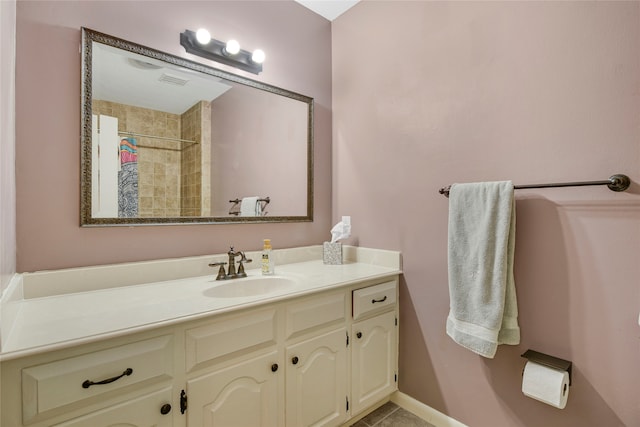 bathroom featuring baseboards, visible vents, a tile shower, and vanity