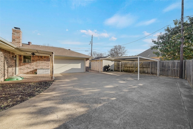 view of side of property with a garage, brick siding, a shingled roof, fence, and a chimney