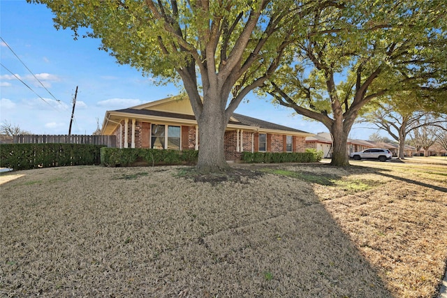 ranch-style house with a front yard, fence, and brick siding