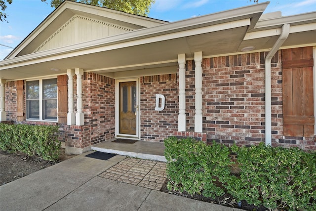 property entrance with a porch and brick siding