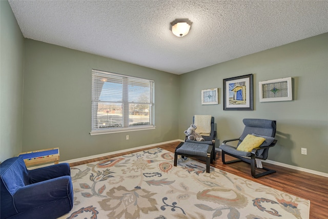 sitting room featuring a textured ceiling, baseboards, and wood finished floors