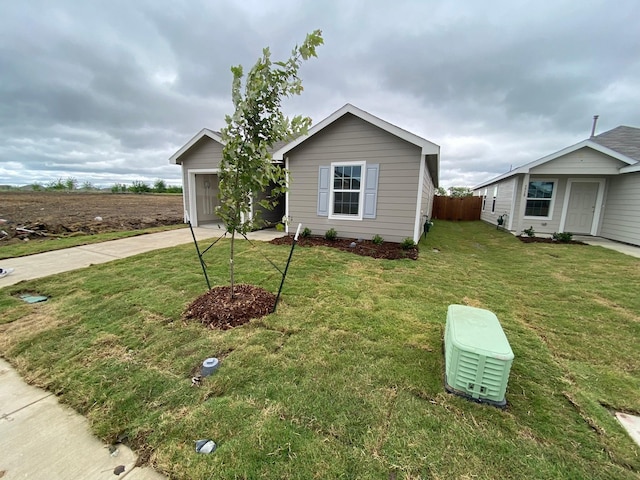 view of front of house with a garage, a front yard, concrete driveway, and fence