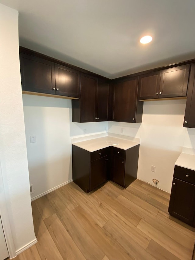 kitchen featuring dark brown cabinetry, baseboards, light countertops, light wood-style floors, and recessed lighting