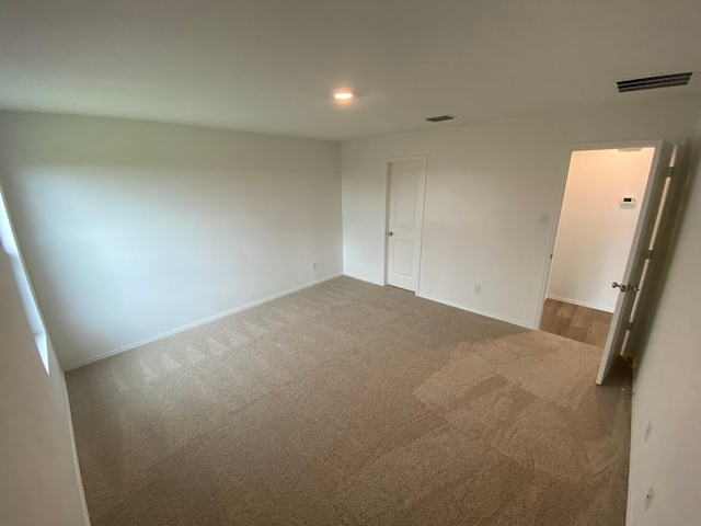 unfurnished bedroom with carpet floors, visible vents, and baseboards