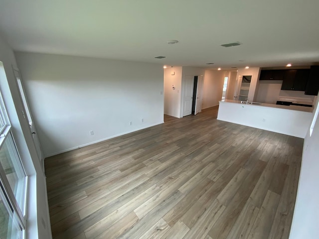 unfurnished living room featuring light wood finished floors, recessed lighting, visible vents, and baseboards