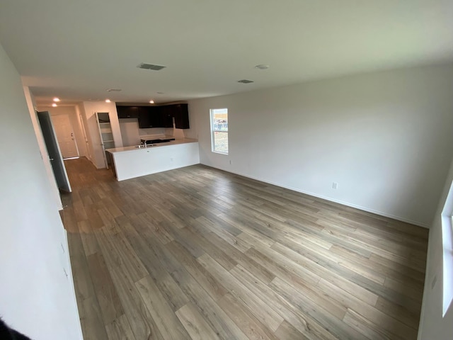 unfurnished living room featuring wood finished floors, visible vents, and baseboards