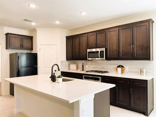 kitchen with dark brown cabinetry, stainless steel appliances, a sink, visible vents, and backsplash