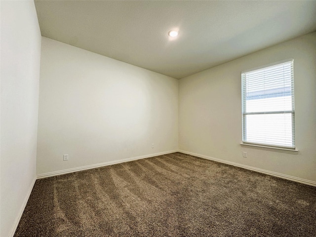 unfurnished room with baseboards, dark carpet, and recessed lighting