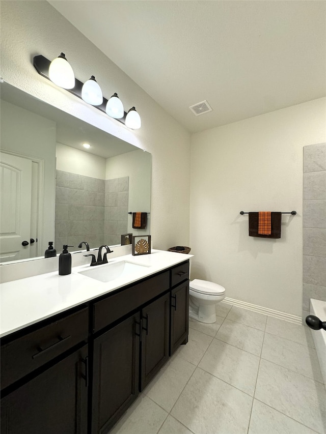 bathroom with visible vents, toilet, vanity, baseboards, and tile patterned floors