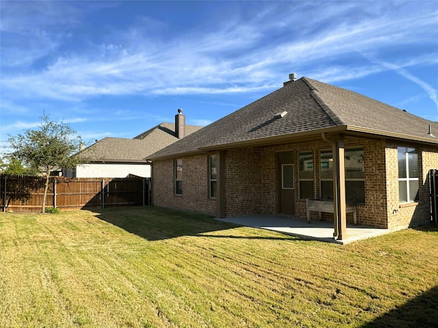 back of property featuring a patio area, fence, brick siding, and a lawn