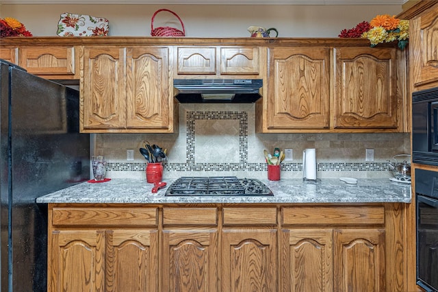 kitchen with decorative backsplash, brown cabinetry, black appliances, and exhaust hood