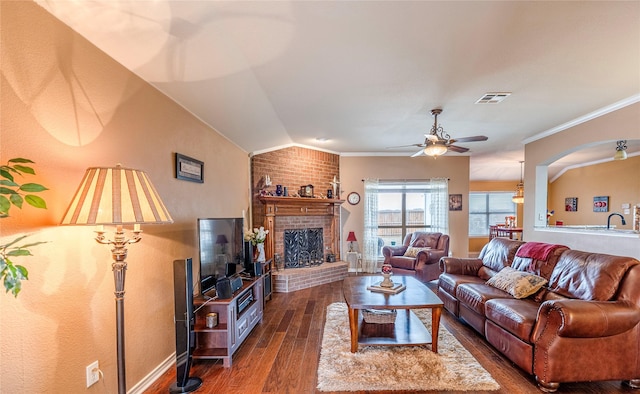 living room featuring lofted ceiling, visible vents, dark wood-type flooring, ornamental molding, and ceiling fan