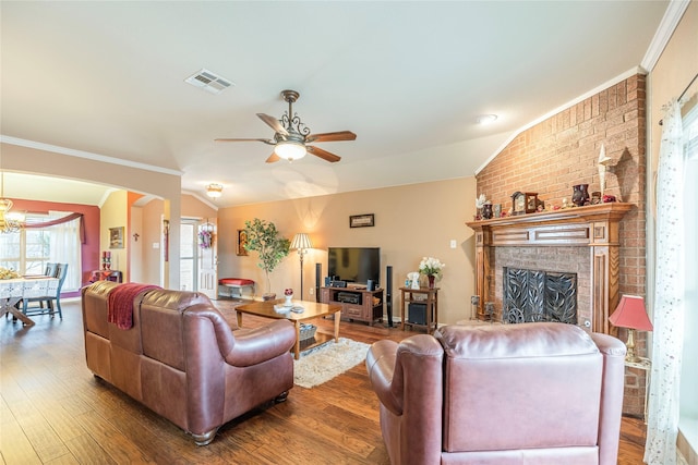 living room with visible vents, arched walkways, lofted ceiling, wood finished floors, and crown molding