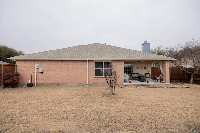 rear view of house featuring roof with shingles, brick siding, a patio, a ceiling fan, and fence