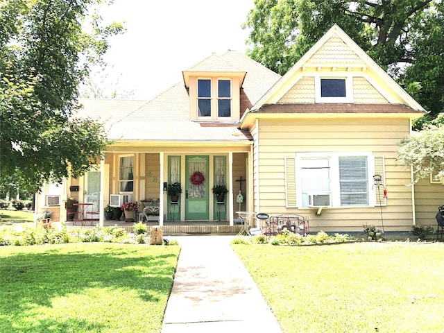 victorian home featuring a porch, a front lawn, and cooling unit