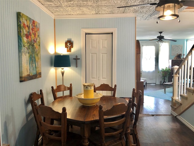 dining space featuring hardwood / wood-style flooring, a ceiling fan, stairs, an ornate ceiling, and wallpapered walls