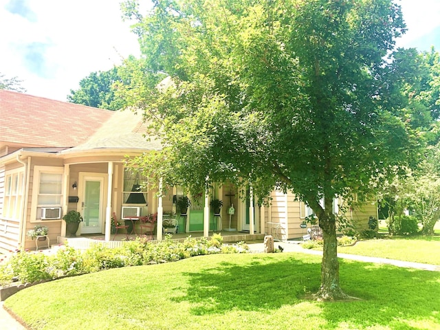 view of front of property with covered porch, a front yard, and cooling unit