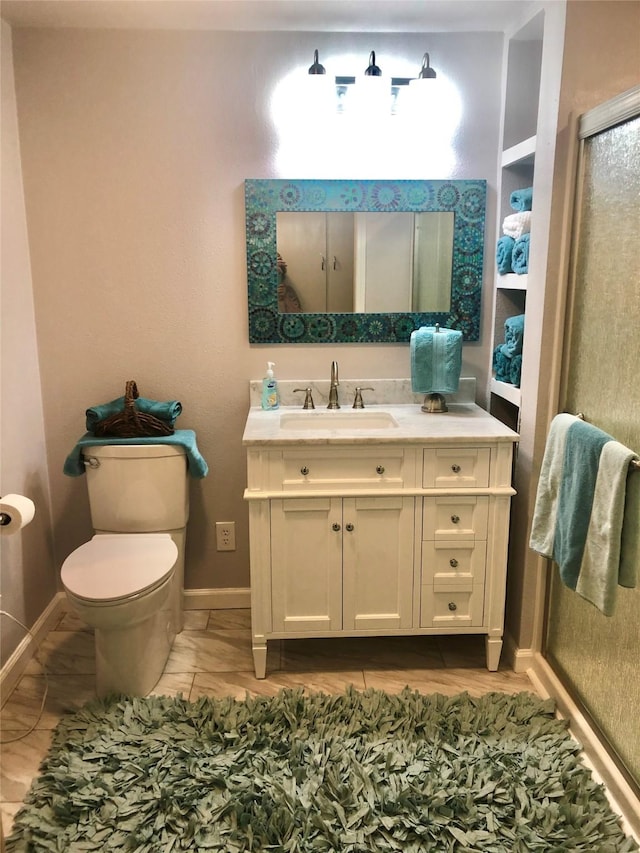 bathroom featuring a stall shower, toilet, vanity, and baseboards