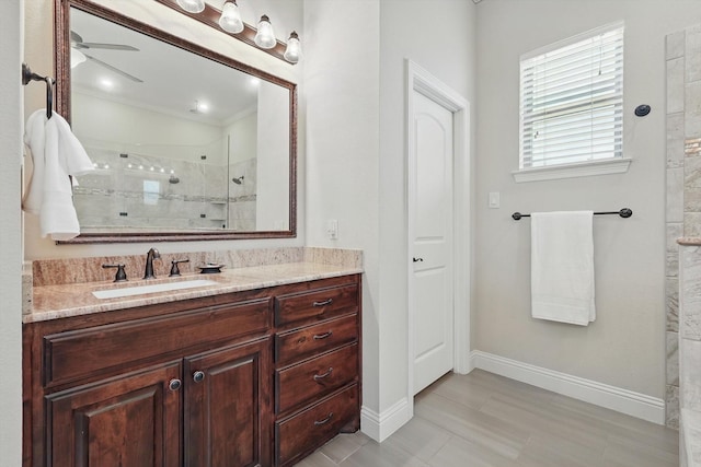 bathroom with a ceiling fan, a tile shower, vanity, and baseboards