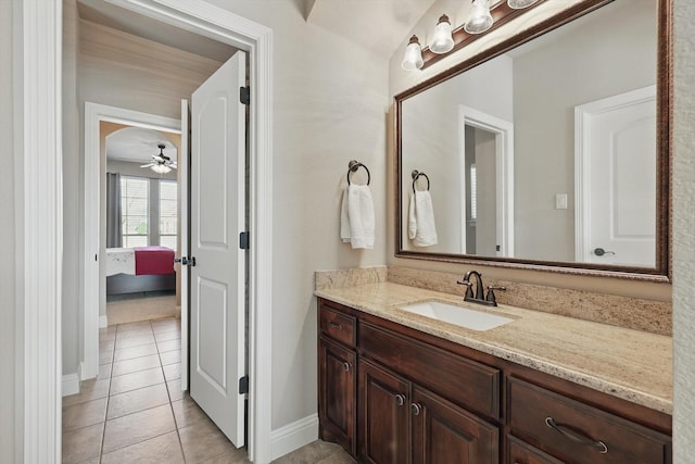 ensuite bathroom with connected bathroom, vanity, ceiling fan, tile patterned flooring, and baseboards