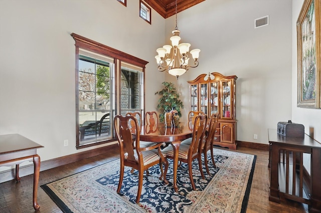 dining room with a notable chandelier, dark wood-type flooring, a high ceiling, visible vents, and baseboards