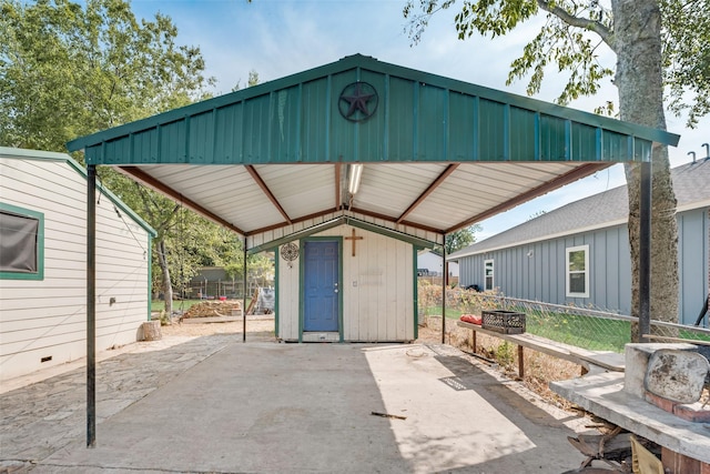 view of patio / terrace with a storage unit, fence, a carport, and an outbuilding