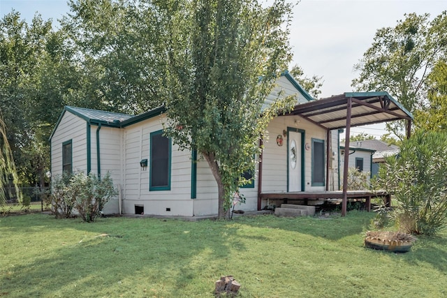 rear view of house featuring crawl space, a yard, and metal roof