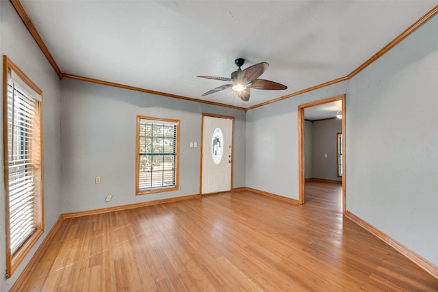 spare room featuring light wood-type flooring, ceiling fan, baseboards, and crown molding