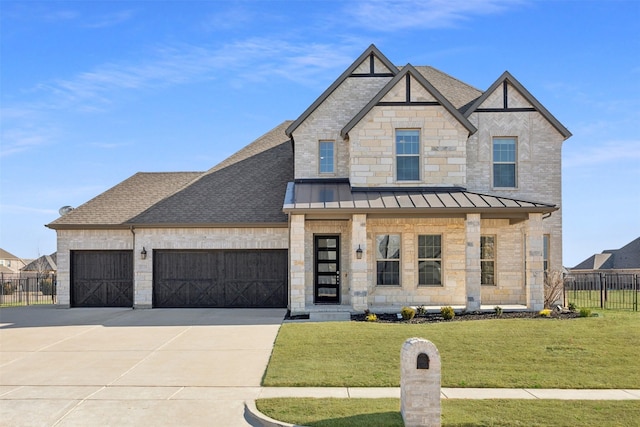 view of front of home with a garage, fence, driveway, a standing seam roof, and a front yard