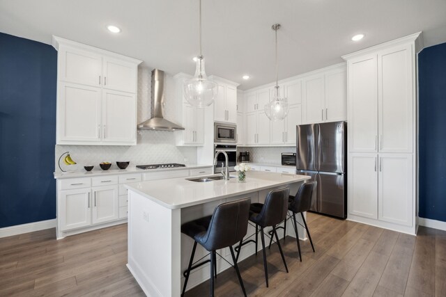 kitchen with light countertops, wall chimney range hood, light wood-style flooring, and appliances with stainless steel finishes