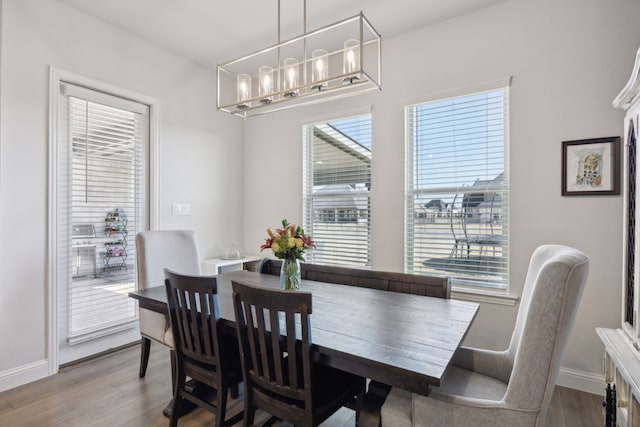 dining area with a notable chandelier, wood finished floors, and baseboards