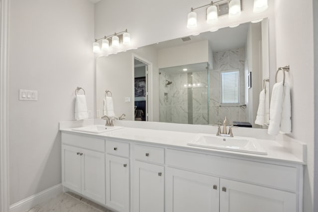 bathroom featuring double vanity, marble finish floor, a marble finish shower, and a sink