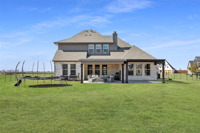 rear view of property with a lawn, an outdoor hangout area, a trampoline, fence, and a patio area